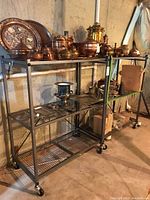 Two metal shelving units holding various copper and metal kitchen items shown as context only. The shelving units are wire metal with caster wheels.