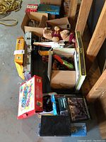 Overview of the lot showing boxes of various toys and games, model kits, a plush teddy bear, a small piano, and train sets in boxes.
