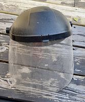 Faceshield showing black headgear and clear protective visor with ratchet adjustment knobs on sides.