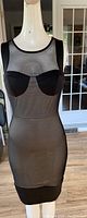 Front view of black sheer sleeveless dress with solid underwire bra cups and fitted silhouette on mannequin
