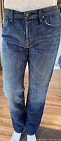 Front view of men's blue denim jeans displaying button and zipper closure with front pockets.