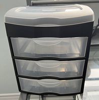 Front view of Eldon desktop storage unit showing three translucent drawers and top clear hinged compartment.