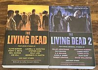 Photo showing The Living Dead and The Living Dead 2 horror anthologies with covers depicting zombies and humanoid figures in dark apocalyptic settings.