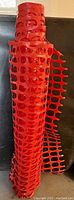 Rolled orange plastic fencing with grid mesh pattern visible