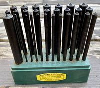 28 transfer punches organized in a green stand showing the punch sizes labeled on the front.