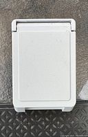 White electrical outlet cover with smooth surface shown closed.