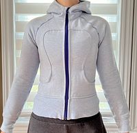 Front view of light gray Lululemon zip-up hoodie worn by model, showing fitted cut, diagonal stitched paneling, zipper with darker lining.