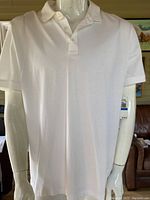 Front view of white Michael Kors men's golf polo shirt displayed on mannequin, showing classic polo design with collar and button placket.