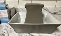 Ceramic rectangular pet water fountain base with gray elevated central section, shown on marble surface.