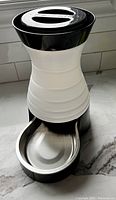 Photo of a black and white Petsafe water dispenser with a stainless steel bowl on a countertop.