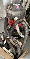 Shop-Vac wet-dry vacuum with hoses and floor brush attachment shown from the front.