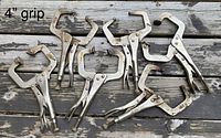 Six Vise-Grip locking C-clamps displayed on a wooden surface, showing their size and condition with visible signs of wear and rust.