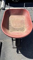 Top view of a red fiberglass tray wheelbarrow showing the inside surfaces and handles extending back.