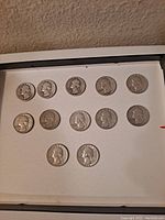 12 Washington silver quarters arranged on display showing obverse side with George Washington profile.