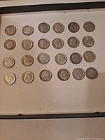Front side of 24 Roosevelt dimes arranged neatly in rows showing the profile of President Roosevelt on each coin.