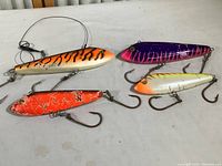 Photo showing all four vintage fishing lures laid out on a surface, showing color patterns and hooks.