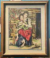 Front view of vintage framed embroidered tapestry showing woman and child in outdoor setting