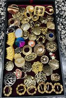 Full top view of assorted scarf and dress clips in black display case with red velvet base.