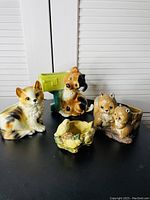 Full view of all five ceramic animal planters on black surface, including a sitting dog, dog with mailbox, two hamsters, and bird nest with chicks.
