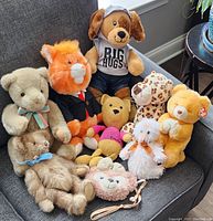 Full group of 9 plush toys arranged on a grey couch, showing variety of animals and styles.