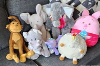 Group photo of seven assorted plush animals laid out on a couch showing variety and condition.