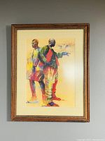 Full view of the framed artwork showing two men standing back-to-back with a bird flying near one.