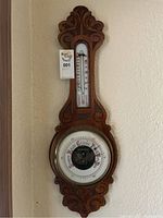 Full view of the antique wood wall thermometer and barometer with carved wood frame mounted on wall.