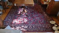 Overhead view of rectangular red floral patterned area rug under dining table