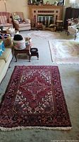 Overview of living room floor showing three rugs: dark red foreground, two light rugs mid and back