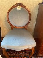 Balloon back chair showing blue upholstered seat and back with carved wooden frame.