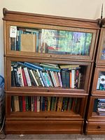 Front view of three-tier wood bankers book case with glass-front doors.