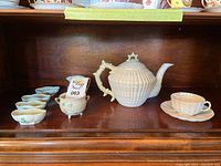 Full display of teapot, small dishes, sugar bowl, creamer, cup and saucer