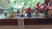 Overview photo of six hand-painted porcelain figurines including red cardinals and flowers on window sill.