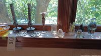 Wide shot showing multiple glass bud holders and decor arranged on a windowsill with natural light.