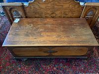 Top view of the wooden blanket chest showing the wood veneer top with visible wear and discoloration marks.