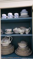 Wide view of shelves holding Royal Albert Silver Birch china tea set including cups, saucers, plates, teapot, and similarly styled dishes