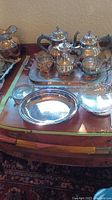 Full view of assorted silver plated serving items displayed on wooden table