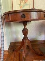 Side view of the round wooden table showing claw feet and central pedestal base.