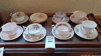 Overview of 7 pairs of tea cups with saucers showing various floral designs and styles.