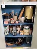 Shelf with vintage baking items including containers, utensils, rolling pin, and cast iron pans, showing full lot content.