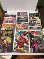 Top view showing 12 assorted comic books including X-Men, Teen Titans, Supergirl, Batman, Ghost Rider, Huntress, Power Man Iron Fist, X-Force, The Titans.