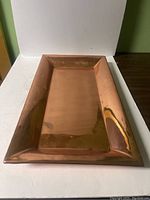 Photo showing the rectangular solid copper tray from a top-down angle, highlighting the flat surface and edges.
