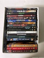 Front view of 17 DVD cases stacked showing titles of superhero and action movies.