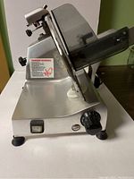 Side view of slicer showing base, power switch, thickness-adjustment knob and blade guard