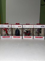 Four Hallmark ornaments in packaging: The Flash, Batman, Harry Potter, and Shuri