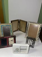 Photo showing seven assorted picture frames with various styles and colors.