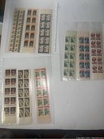 Three groups of plate block stamps in plastic protector sheets, including portraits, football design, and building motifs