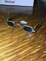 Front angled view of the antique sharpshooters glasses showing octagonal green lenses and brass extendable arms with folding side shields.