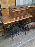 Full view of antique Singer treadle sewing machine with wooden cover in closed position, showing drop leaf and drawer fronts.