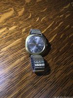 Angled side view of the watch showing the gold-tone case and expansion wristband.